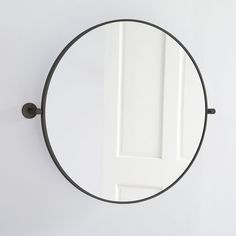 a round mirror hanging on the wall next to a white door with a black handle