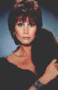 the woman is wearing a black dress and fur stole around her shoulders, posing for a photo