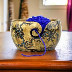 a wooden bowl sitting on top of a table with blue yarn in the middle of it