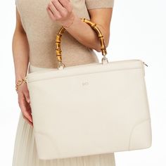 Meet Emily, exquisitely elegant, this handbag is made from gorgeous pebbled leather and designed for work or play with genuine bamboo handles and a spacious, organized interior that fits a 14"laptop and features an unexpected, but classic, striped lining. Add a classic foil monogram to make it yours.    15"w x 5"d x 11.5"h  Please see Product Information for more dimensions.  Pebbled leather, bamboo, striped lining (92% polyester, 8% cotton 8%)  Clean with a dry cloth.  Imported.  Monogramming is foil debossed. Elegant Beige Briefcase With Leather Handles, Luxury Top Handle Satchel With Laptop Sleeve, Luxury Satchel With Laptop Sleeve And Top Handle, Luxury Tote Satchel With Laptop Sleeve, Luxury Satchel With Laptop Sleeve, Elegant Satchel With Laptop Sleeve And Double Handle, Elegant Beige Satchel For On-the-go, Elegant Briefcase With Laptop Sleeve And Double Handle, Elegant Laptop Bag With Double Handle And Sleeve