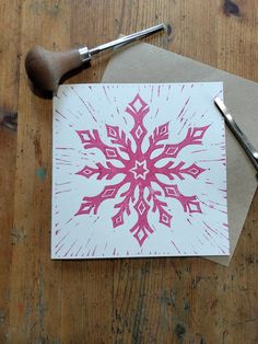 a piece of paper with a pink and white snowflake on it next to a pair of scissors