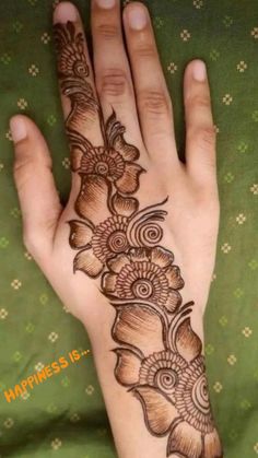 a woman's hand with a henna tattoo on it and flowers in the middle