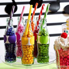 there are many candy in the bottles with straws on them and one has a clown hat