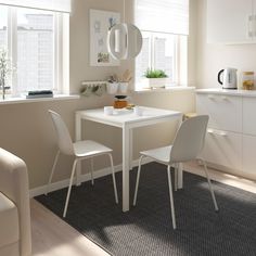 a white table and two chairs in a small room with light coming through the windows