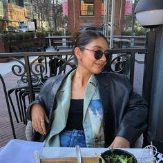 a woman sitting at a table in front of a plate of food with salad on it