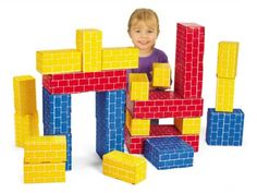 a young boy is playing with blocks in the shape of a building block set and smiling