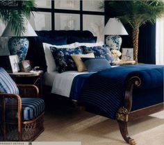 a bed room with a neatly made bed next to a window and a palm tree