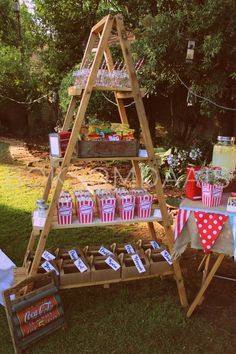 an outdoor party with red and white striped paper cups, popcorn buckets and soda bottles