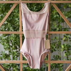 a pink and white swimsuit hanging on a wooden fence next to green plants in the background