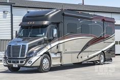 a silver and black rv parked in front of a storage building on the side of a road