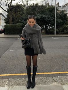 black mini skirt paired with a grey sweater ootd Grey Dress Fall Outfit, Grey Sweater With Skirt, Sweater Outfits With Skirts, Winter Black Mini Skirt Outfit, Outfit With Skirt And Boots, Black Skirt Tights Boots Outfit, Black Mini Skirt Outfits Fall, Long Coat And Skirt Outfit, Winter Hunter Boots Outfit