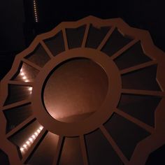 a circular light fixture in the middle of a dark room with lights on it's sides