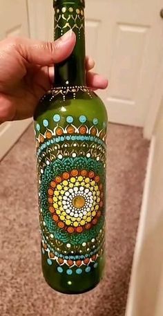 a hand holding a green bottle with designs on it