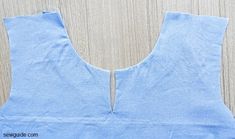 the back of a blue top that has been cut out and is sitting on a wooden surface