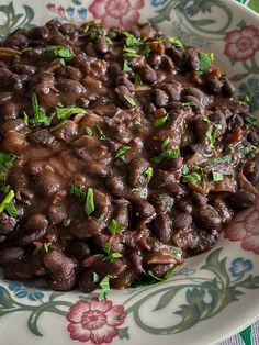 a close up of a plate of food with beans and herbs on it, surrounded by flowers