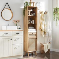 a bathroom with white cabinets and towels on the shelf next to it is also decorated with greenery