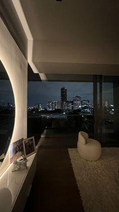 a living room filled with furniture and a large window overlooking the city at night time