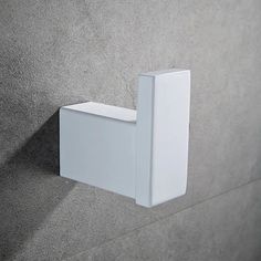 a close up of a white square object on a gray wall with grey cement behind it