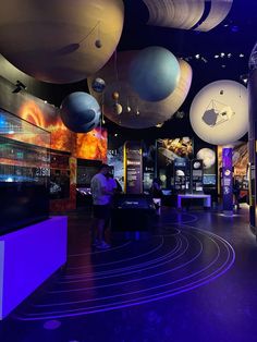 a man standing in front of an exhibit with planets hanging from it's ceiling