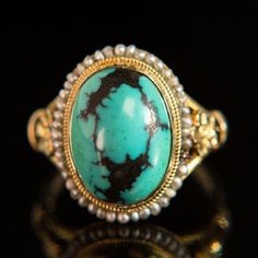 Description This beautiful, intricately crafted ring features a striking turquoise cabochon surrounded with a halo of delicate seed pearls. Buttery and vibrant 14k yellow gold brings out the stones' gorgeous natural hues of turquoise and cream, lending a bright, ethereal quality to this beautiful ring. Featuring a hand Heirloom Oval Turquoise Cabochon Ring, Turquoise Cabochon Heirloom Ring, Heirloom Yellow Gold Turquoise Cabochon Ring, Fine Jewelry Turquoise Cabochon Ring In 14k Gold, Fine Jewelry 14k Gold Turquoise Cabochon Ring, 14k Gold Turquoise Cabochon Ring, Heirloom Turquoise Cabochon Jewelry, Heirloom Style Turquoise Cabochon Wedding Ring, Wedding 14k Gold Turquoise Cabochon Ring