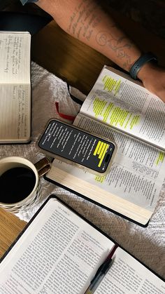 an open book on top of a table next to a cup of coffee and two notebooks