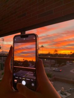 someone is taking a photo with their cell phone at sunset or sunrise over a parking lot