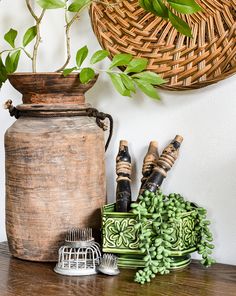 a wooden table topped with green plants next to a potted plant and other items