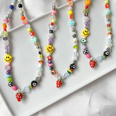 three colorful beaded necklaces with smiley faces on them sitting on a white plate