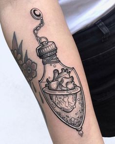 a woman's arm with a heart in a bottle tattoo on it