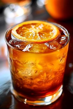 an orange slice is sitting on top of a glass filled with liquid and ice cubes