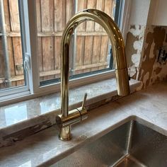 a kitchen sink in front of a window with peeling paint on the wall behind it