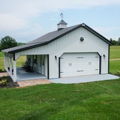 a large white garage sitting in the middle of a lush green field