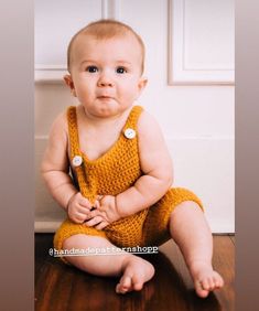 a baby sitting on the floor wearing a yellow romper