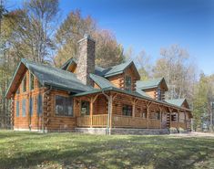 a large log cabin sits in the middle of a wooded area with trees and grass