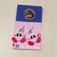 a pair of pink and white earrings on top of a card