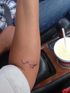 a woman's arm with a tattoo on it and a drink in the background