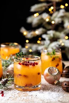 two glasses filled with orange liquid and garnished with cranberries on a table