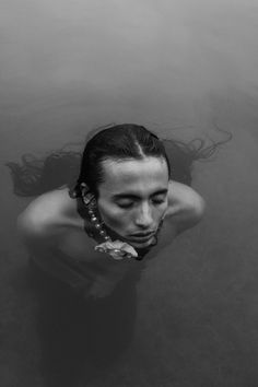 a woman is floating in the water with her hair up and wearing a braid around her neck