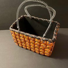 an orange and black basket with silver wire on the bottom, sitting on a gray surface