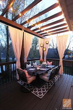 an outdoor dining area is lit up with string lights and drapes over the table