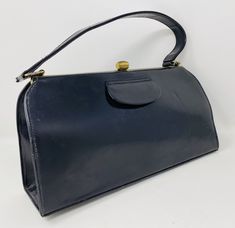 This is a really lovely vintage navy blue leather Kelly style handbag, made in England.  It is in good condition, apart from a vertical line indentation on the front right, as shown in the photos - so if you want your handbag to be near perfect, this isn't the bag for you - but if you're ok with it having this small flaw, then it *is* the bag for you. I've adjusted the price to take account of the indentation.  The dimensions are 11 x 5.5 x 3 inches.  The interior is a nice silky blue.  (not fou Maroon Leather, Patent Leather Handbags, How To Make Handbags, Tan Suede, Black Patent Leather, Leather Handbag, Blue Leather, Purses And Handbags, Patent Leather