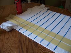 the table is covered with strips of paper and tape to make a t - shirt