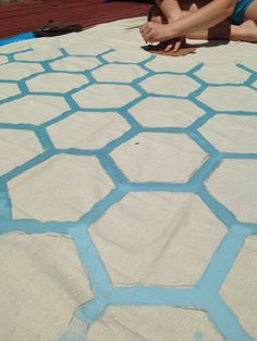 a woman laying on top of a white and blue blanket next to a wooden floor