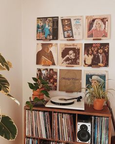 a record player sitting on top of a wooden shelf next to a wall filled with records