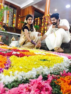 a man and woman sitting on the ground surrounded by flower petals in front of them