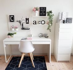 a white desk sitting on top of a wooden floor next to a black and white rug