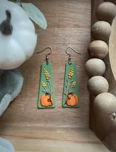 These sweet little pumpkin lie on beautiful sprigs of golden rod which standout against a lovely fall green backdrop. Dangling from stainless steal earring wires, these are the perfect statement earrings for fall or Thanksgiving!   These are super light weight, but from the top of the ear wire to the bottom of the earring is almost 3 inches long. Check out my shop for more unique items!  All orders over $35 ship for free! Thanksgiving Earrings, Olive Green Background, Fall Green, Floral Pumpkin, Golden Rod, Hand Painted Earrings, Green Backdrops, Painted Earrings, Pumpkin Earrings