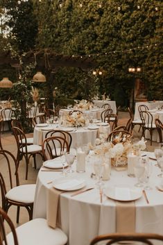 tables and chairs are set up with white linens for an outdoor wedding reception in the garden