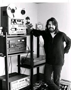 a man standing next to a shelf with electronics on it