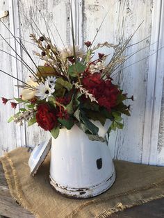 a white watering can filled with red and white flowers